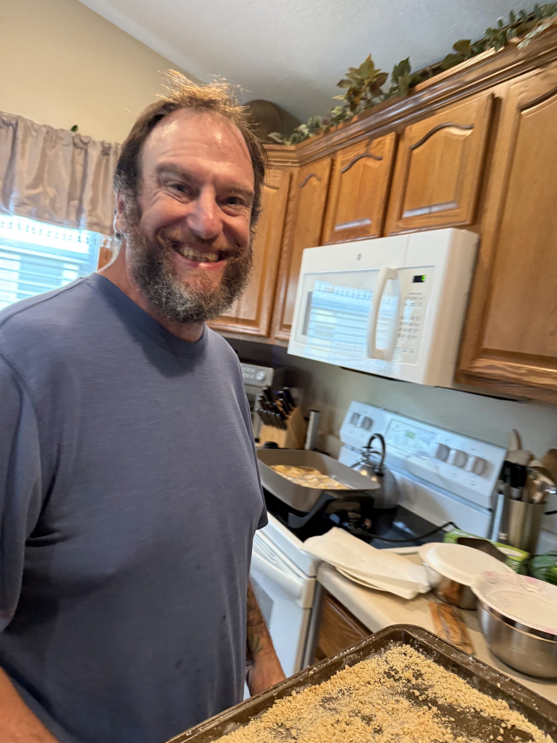 Wade smiling in K&K Kitchen while preparing breaded swordfish beside the stove.