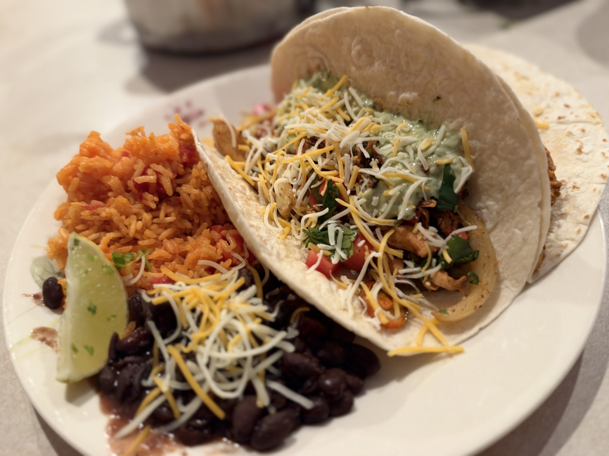 Loaded rotisserie chicken fajita with Spanish rice, black beans, cheese, cilantro, tomato, guacamole and lime