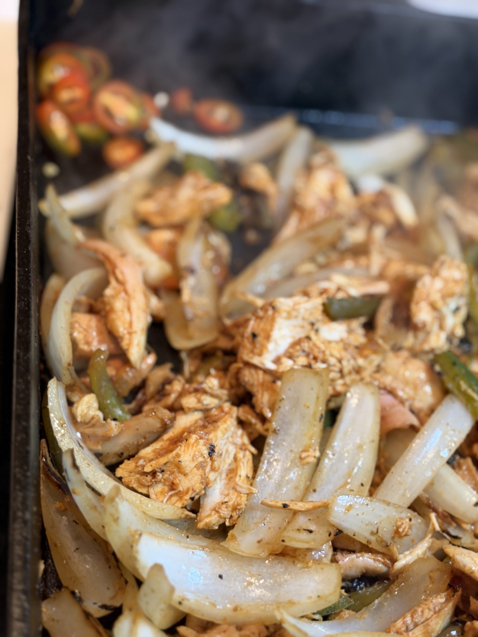 Rotisserie chicken, charred onions, peppers and jalapeño cooking together in the skillet