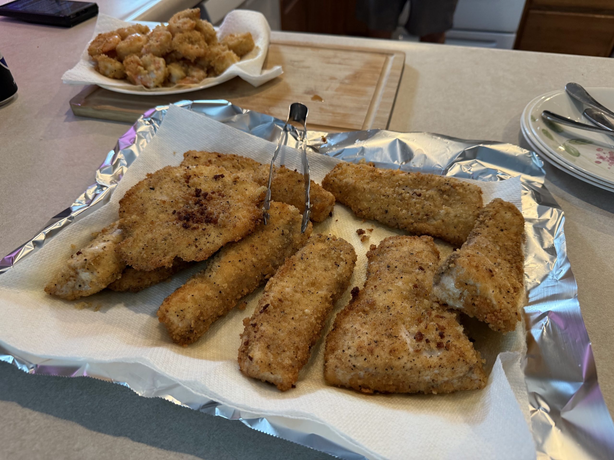 Lightly fried breaded swordfish fillets resting on paper towels after cooking.