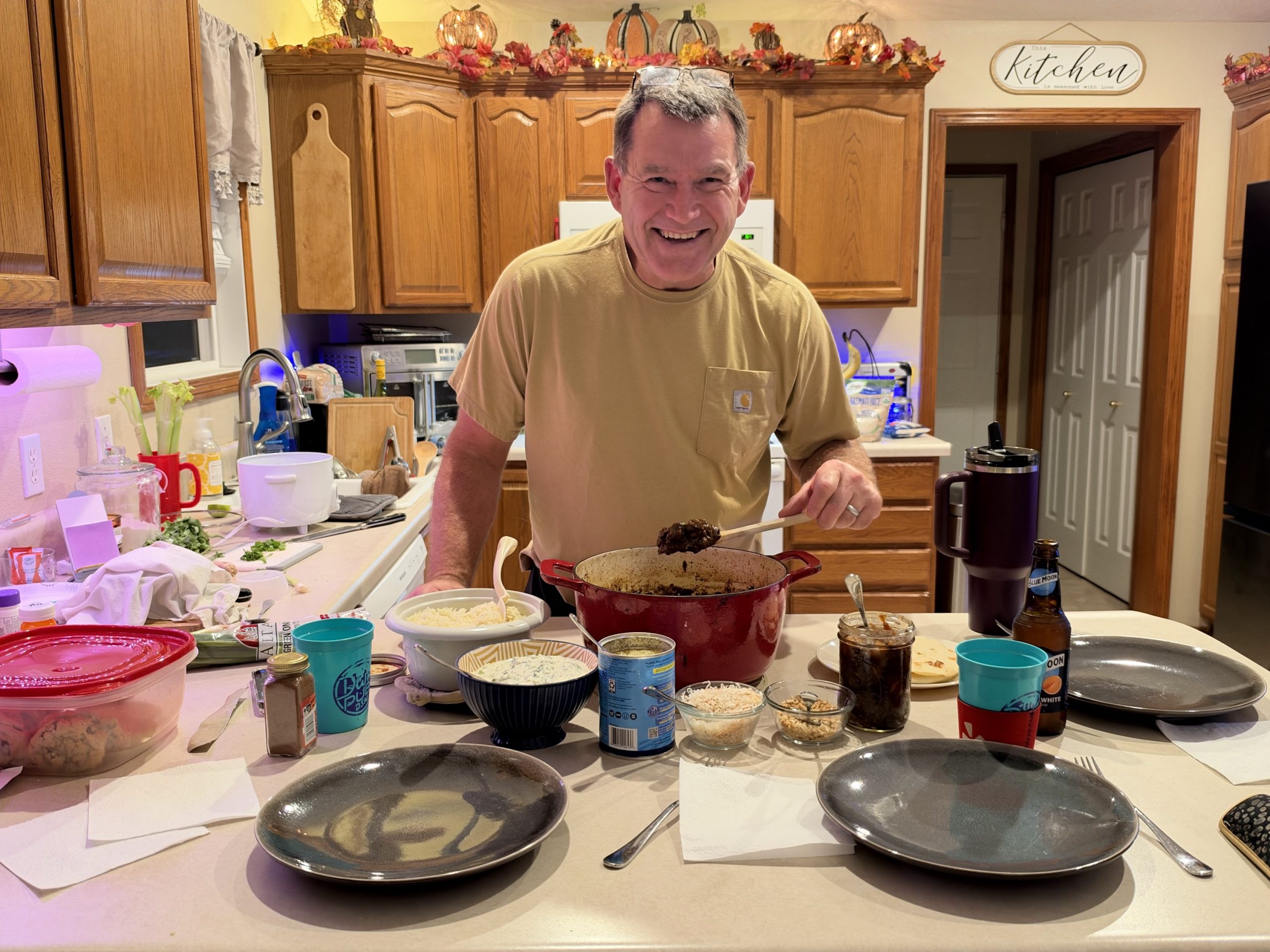 Kirk smiling behind the counter with the big Dutch oven and bowls of toppings