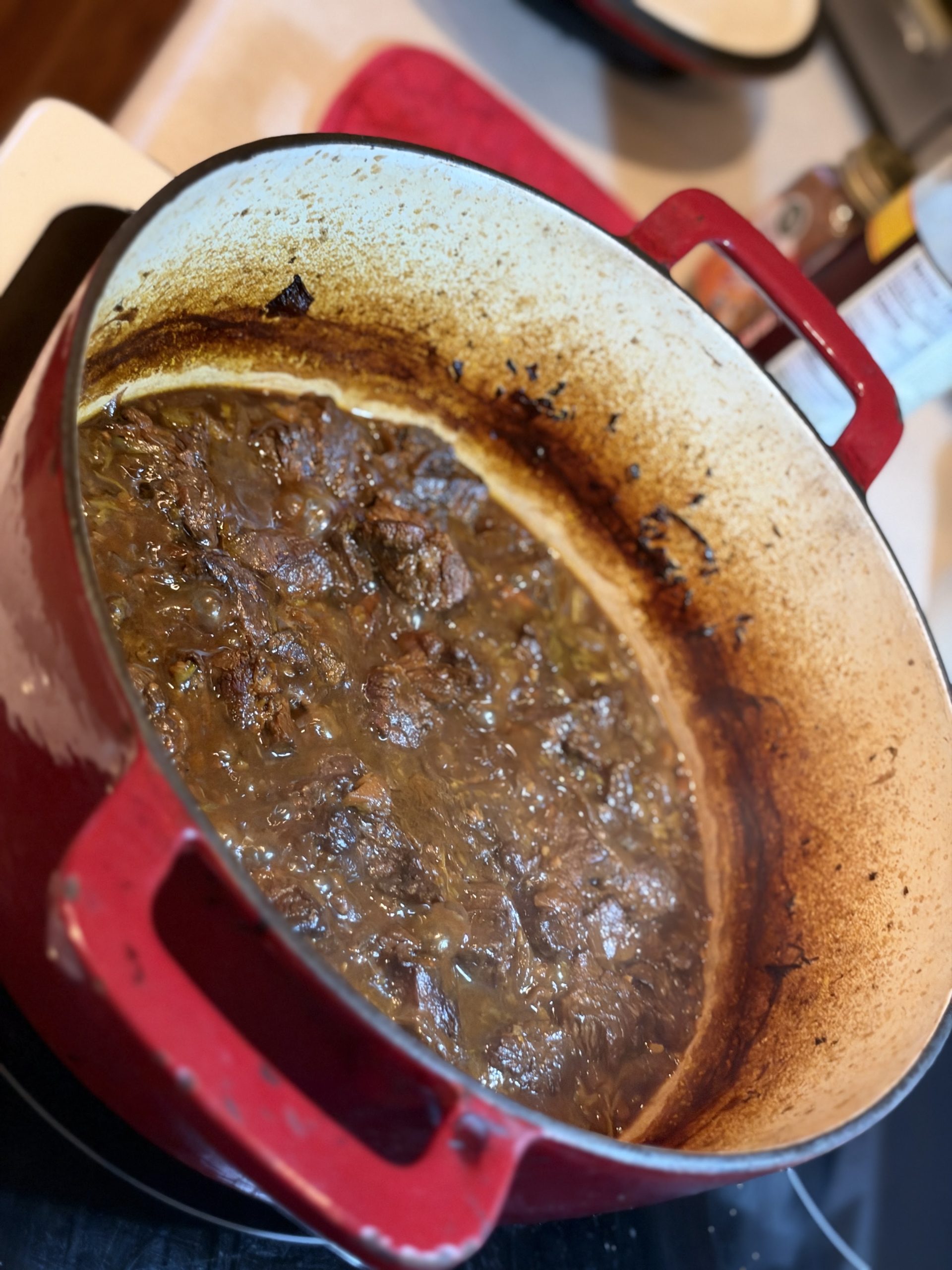 Deep rich brown beef curry in the Dutch oven after braising